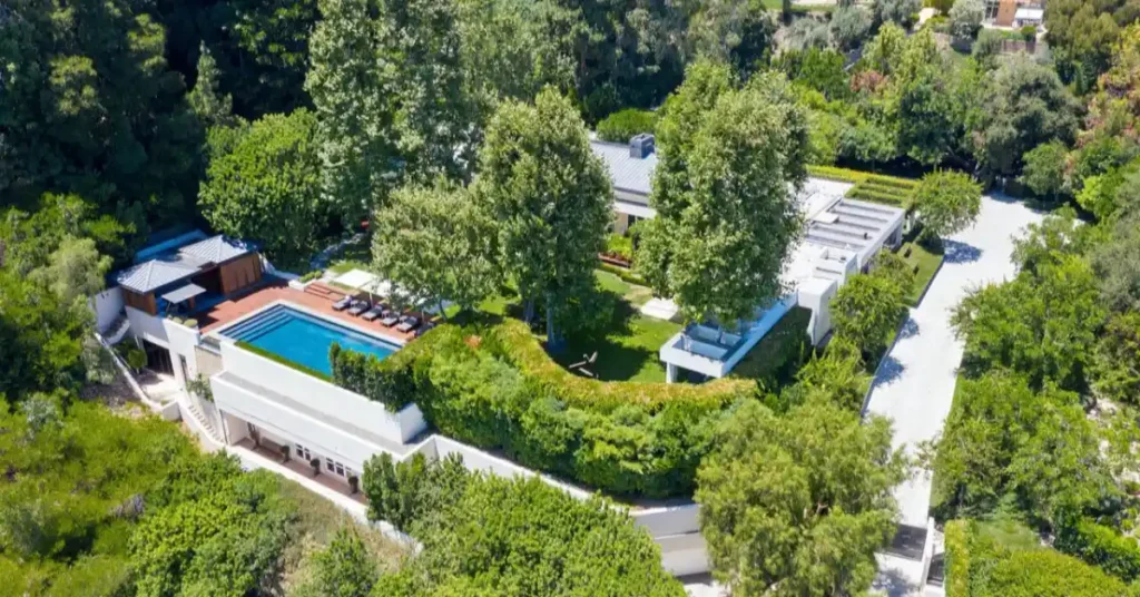 Ryan Seacrest house in Beverly Hills featuring modern white architecture, resort-style swimming pool, and lush landscaping that exemplifies his luxury real estate portfolio.