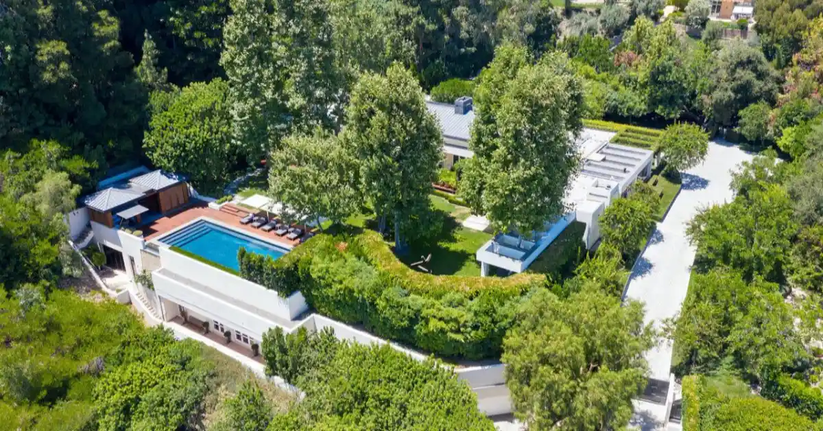 Ryan Seacrest house in Beverly Hills featuring modern white architecture, resort-style swimming pool, and lush landscaping that exemplifies his luxury real estate portfolio.